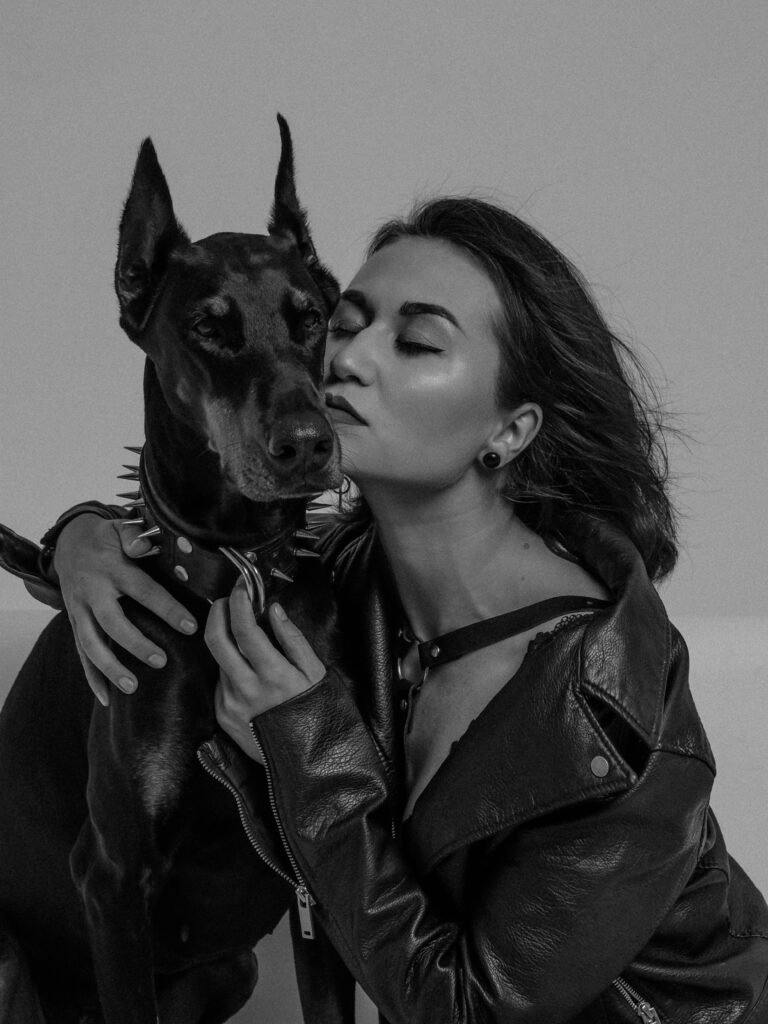 zipwp-image-9541969 Elegant black and white portrait of a woman embracing a Doberman, showcasing togetherness.